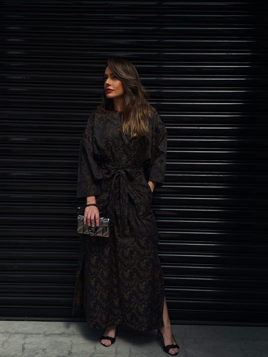 Ensaio de moda: mulher de vestido longo estampado diante de uma porta de aço escura